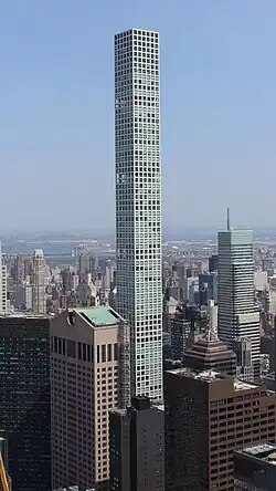 The middle stories of 432 Park Avenue, as seen from the observation deck of another building several blocks away. 432 Park Avenue is a thin tower with a square floor plan. The white facade has square windows.