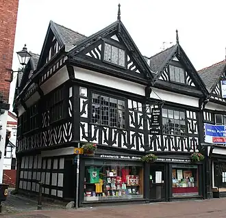 A black-and-white building in a corner position, with two gables to the front and three to the side.