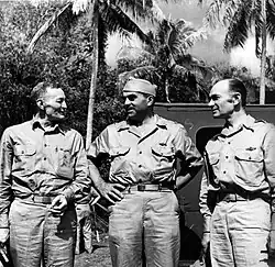 Black and white photograph of three men in khakis in a tropical area