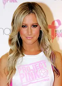 A woman with long blonde hair wearing a white t-shirt.
