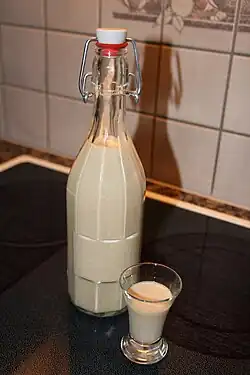 A glass bottle and a shot glass on a hob, both containing Atholl brose