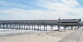 A long building built on a narrow pier extending out from the beach to the ocean