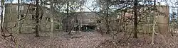 A panoramic image showing a large "H-shaped" building overtaken by nature due to Bainbridge's abandoning.
