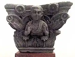 Indo-Corinthian capital representing a Buddhist devotee wearing a Graeco-Roman coat with fibula. Butkara Stupa, National Museum of Oriental Art, Rome.