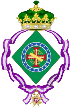 Coat of arms consisting of a shield with a green field with a golden armillary sphere over the red and white Cross of the Order of Christ, surrounded by a blue band with 19 silver stars; the bearers are two arms of a wreath, with a coffee branch on the left and a flowering tobacco branch on the right; and above the shield is an arched golden and jeweled crown