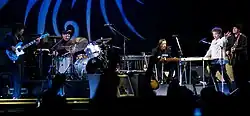 Dylan together with five members of his band onstage. Dylan, dressed in a white shirt and black pants, is second from right.