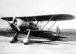 A black and white photograph of a single-propeller biplane on the ground