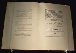 Two pages of a book on exhibition. The right page has three signatures.
