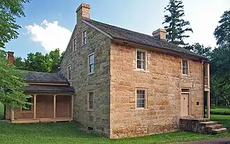 Two-and-a-half-story stone house with a small one-story addition