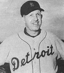 A man in a light baseball uniform and dark cap