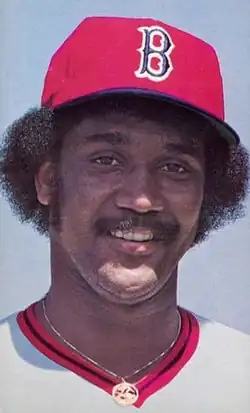 A man in a white baseball jersey and red cap