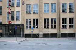 An office building of several stories with many windows, and an entrance visible