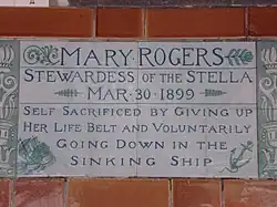 A tablet formed of two large tiles, bordered by green flowers in the style of the Arts and Crafts movement