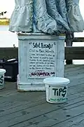 A tip jar and a sign titled "Salut, Peasants!"