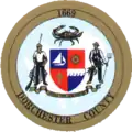 A round seal with a shield, two figures flanking the shield, and a gold border