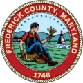 A round seal depicting a farmer in the countryside with a red border