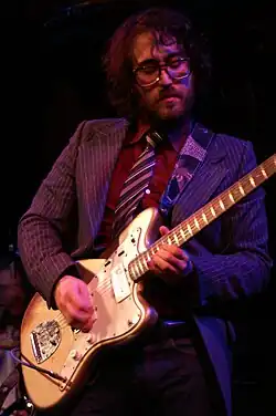 A man with a beard playing guitar