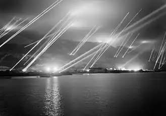 The Rock of Gibraltar, seen from the west, with at least 23 searchlights sending beams of light up into the night sky