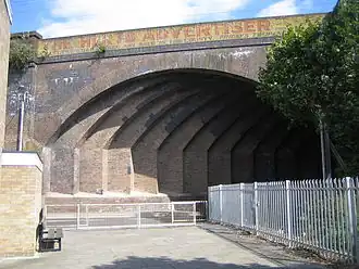 A wide brick arch spanning a narrow road at an oblique angle