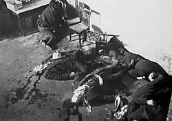 Six men lie dead on the floor with blood splattered around them