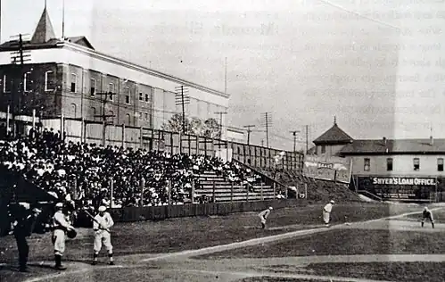 A black and white photograph of home plate and the left field bleachers at a ballpark