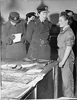 Air Chief Commandant Lady M E Welsh, Director of the WAAF, talking with Leading Aircraftwoman Marjorie Nixon in the Sorting Room of the 2nd Tactical Air Force Photographic Negative Library at Keerbergen, during her visit to the WAAF in Belgium. Wing Officer A Stevens stands to the left of Lady Welsh.