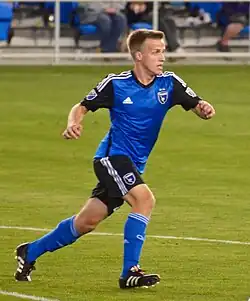 A man wearing a blue soccer uniform running on a field.