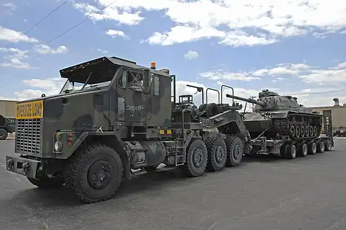 An Oshkosh M1070A0 HET and a DRS M1000 semi-trailer hauling an M60 Patton tank
