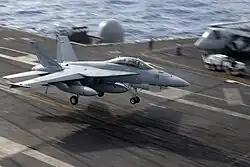 Jet aircraft with landing gear extended flying in a nose-high attitude.